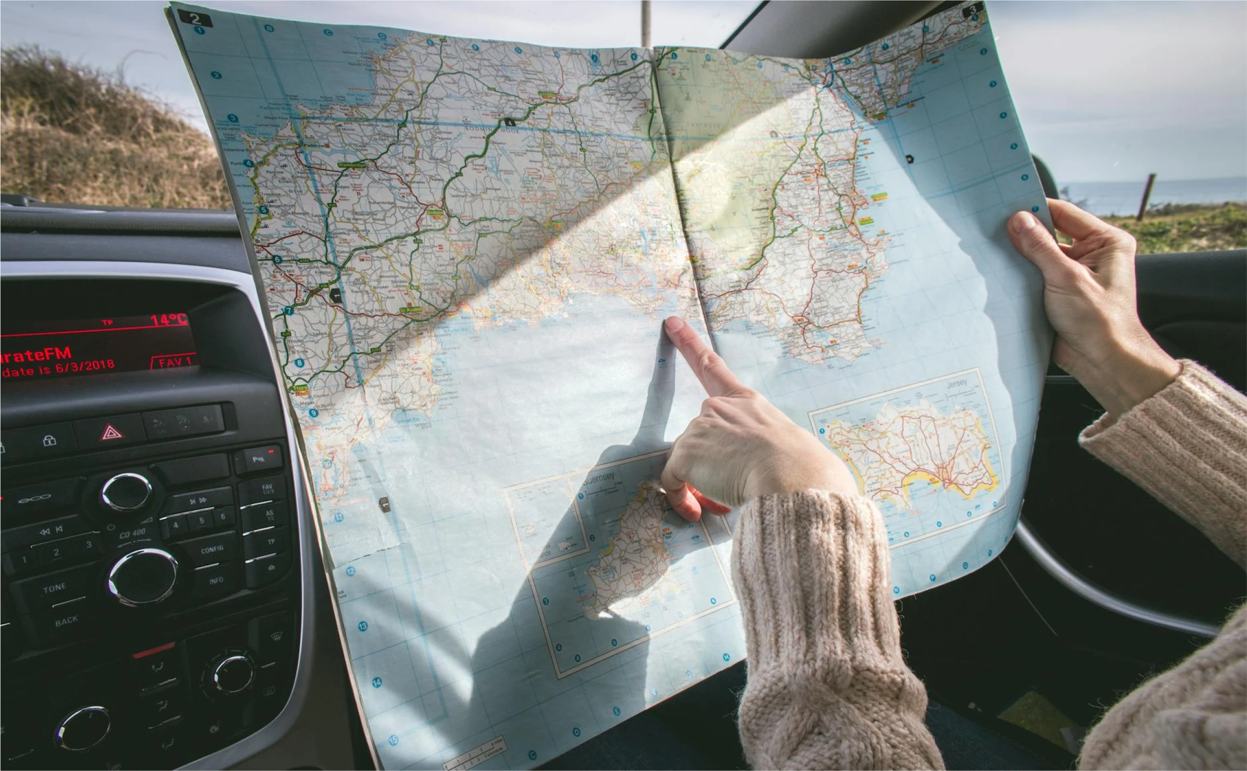 Une personne assise dans une voiture montre quelques chose sur une carte