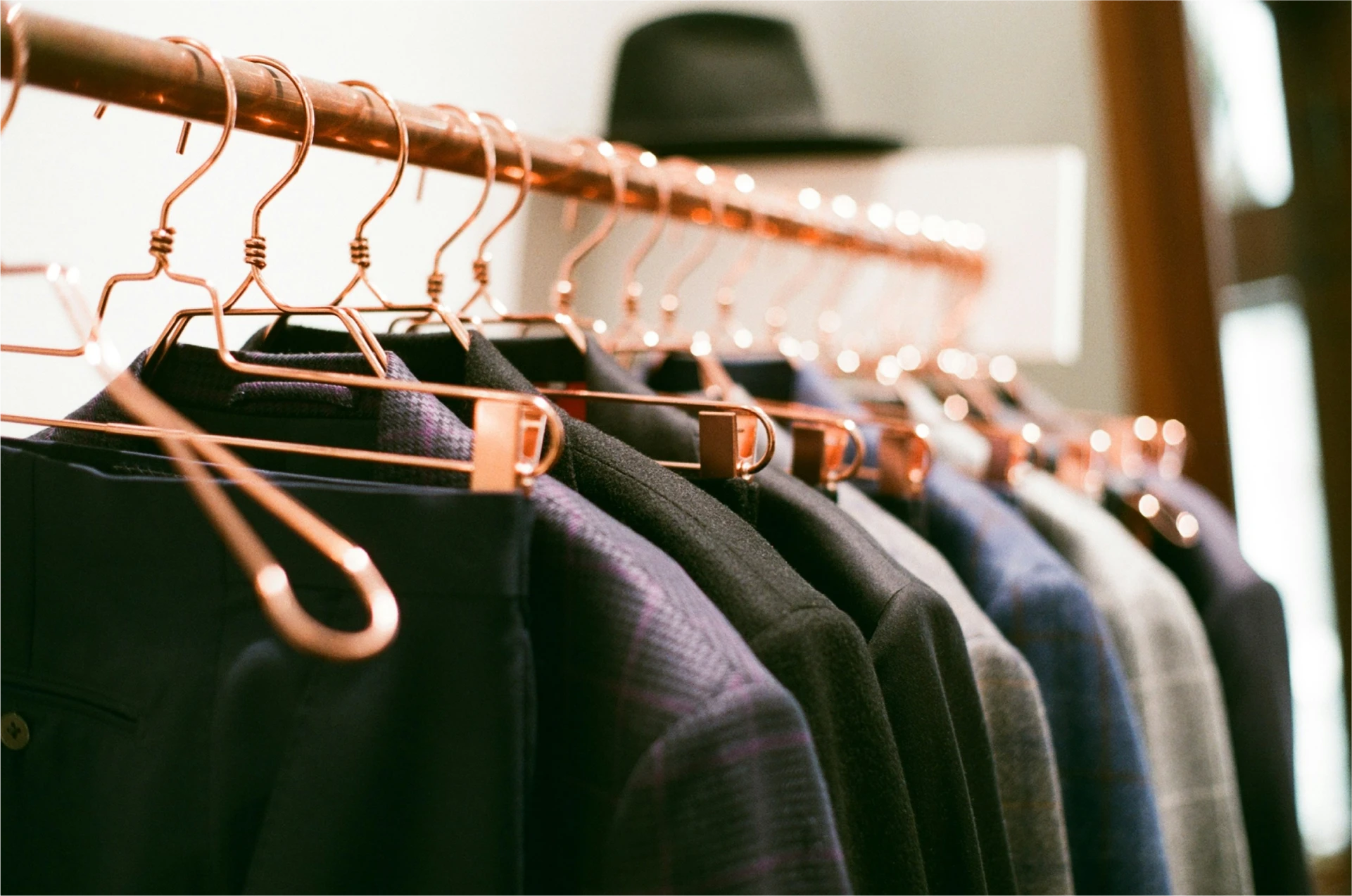 Des vestes de costumes sont posées en ligne sur une tringle à l'aide de cintres.
